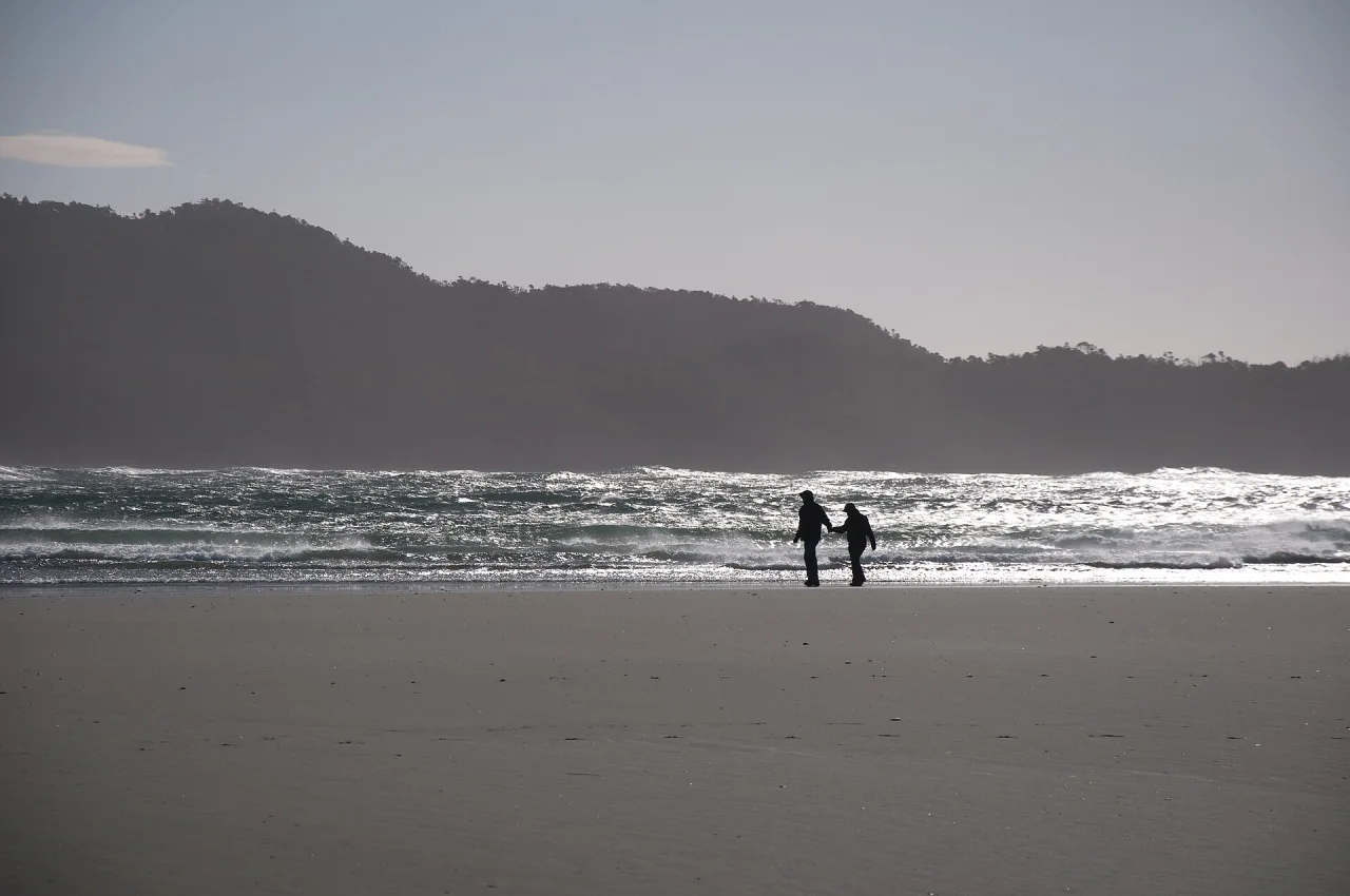 Surfers beside the breakers at Chesterman Beach in winter light
