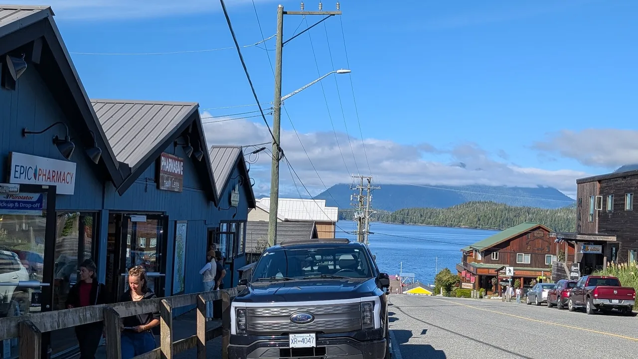 Shops and cafés along a street in downtown Tofino with the inlet beyond
