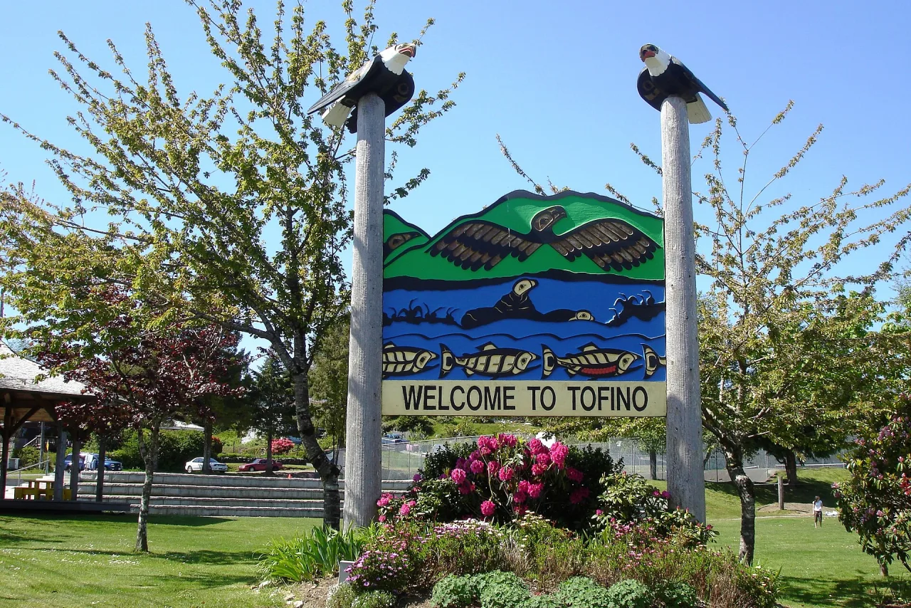 The carved Welcome to Tofino sign among flowers at the entrance to town